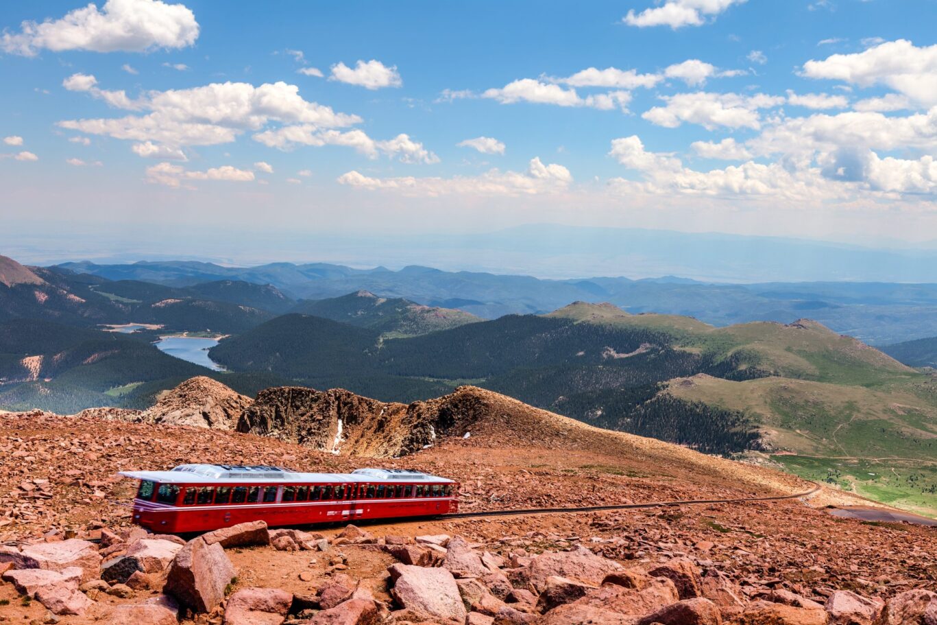 Scenic view of Pikes Peak Cog Railway train climbing the mountain with panoramic Rocky Mountain landscape in Colorado Springs.
