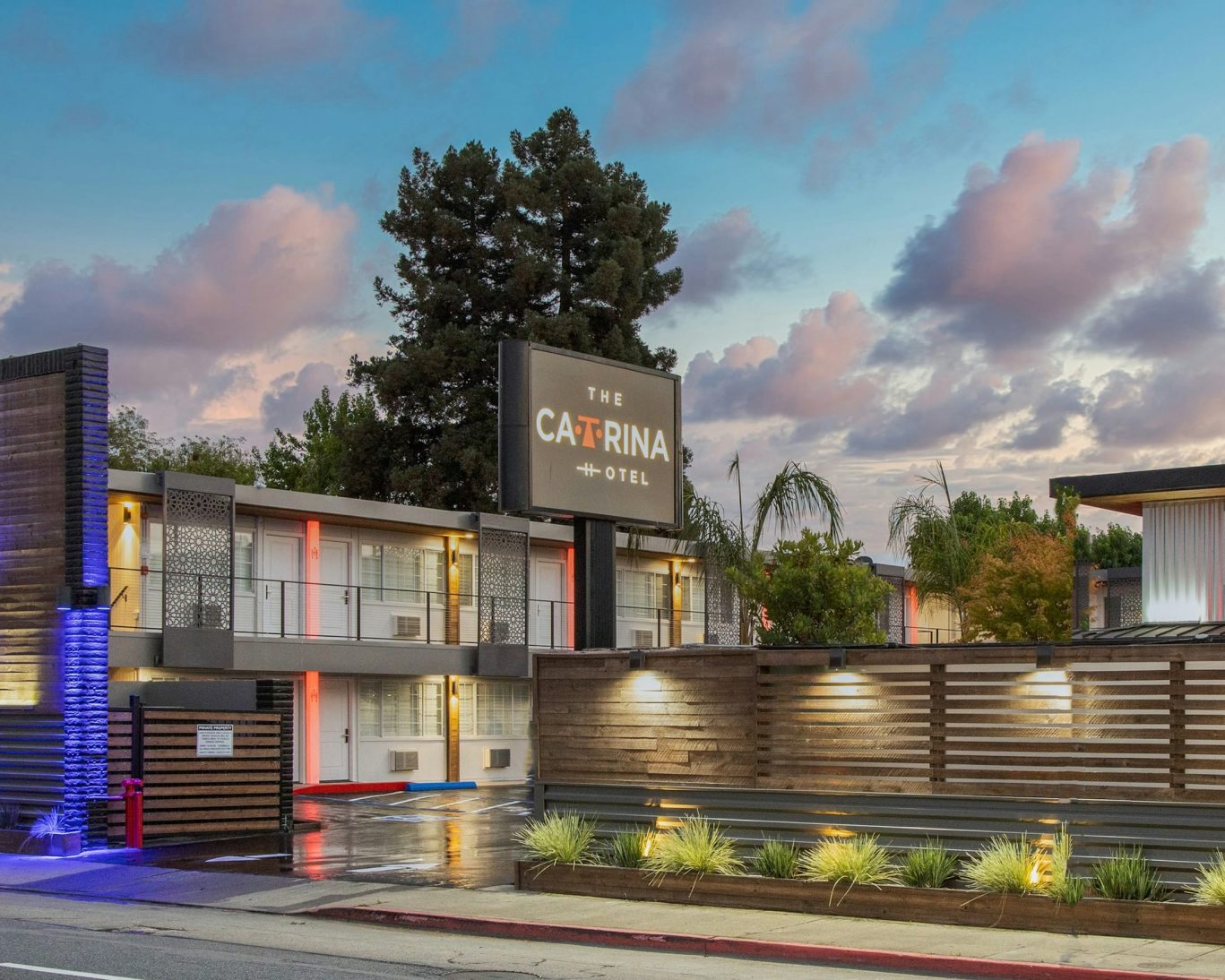 Modern exterior of The Catrina Hotel at dusk with stylish lighting and palm trees