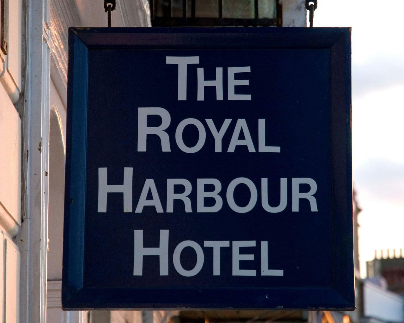 Sign for The Royal Harbour Hotel Ramsgate hanging outside the entrance on a traditional blue background.
