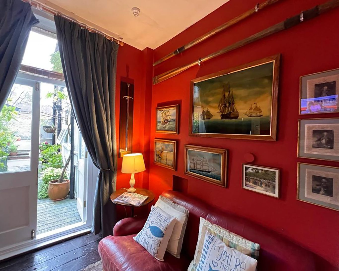 Nautical-themed sitting area at The Royal Harbour Hotel Ramsgate with maritime paintings and garden view.