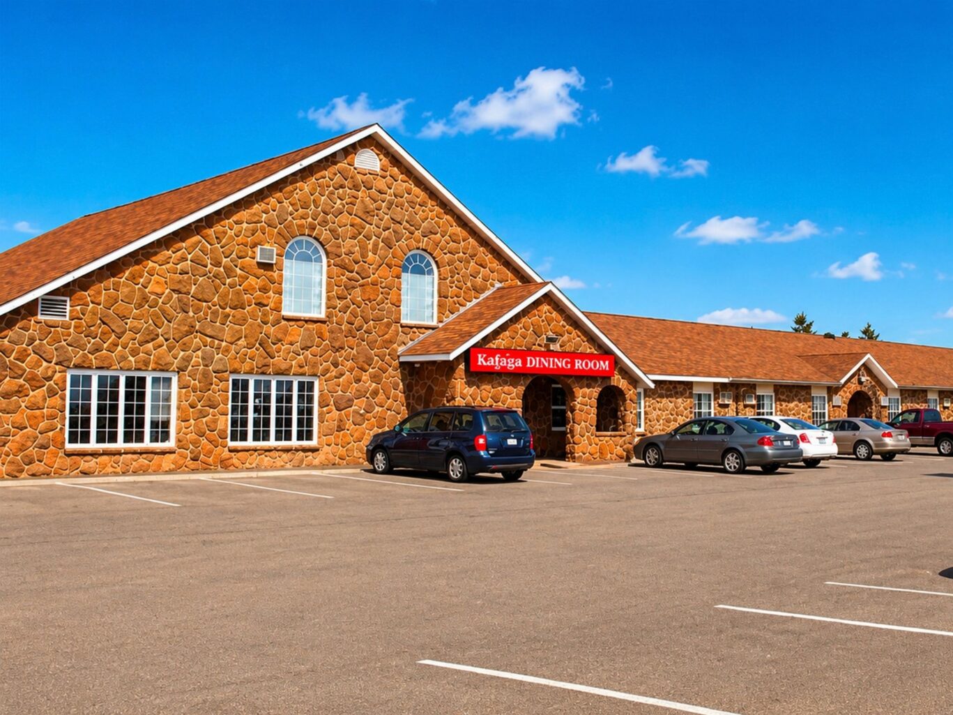 Exterior of Travellers Inn Summerside with large parking lot and on-site dining at Krigina’s Dining Room.