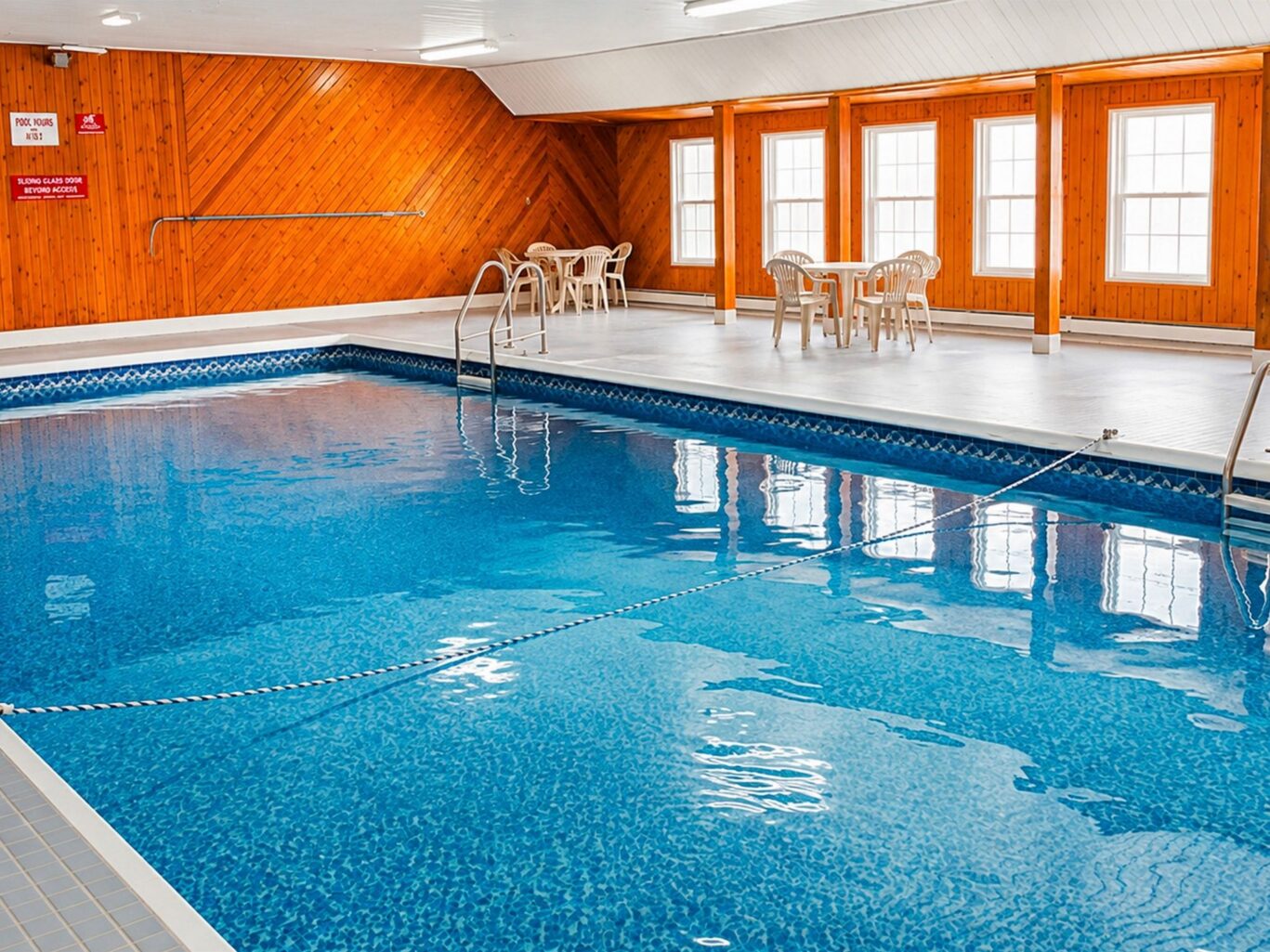 Indoor swimming pool with natural light and seating area at Travellers Inn Prince Edward Island.