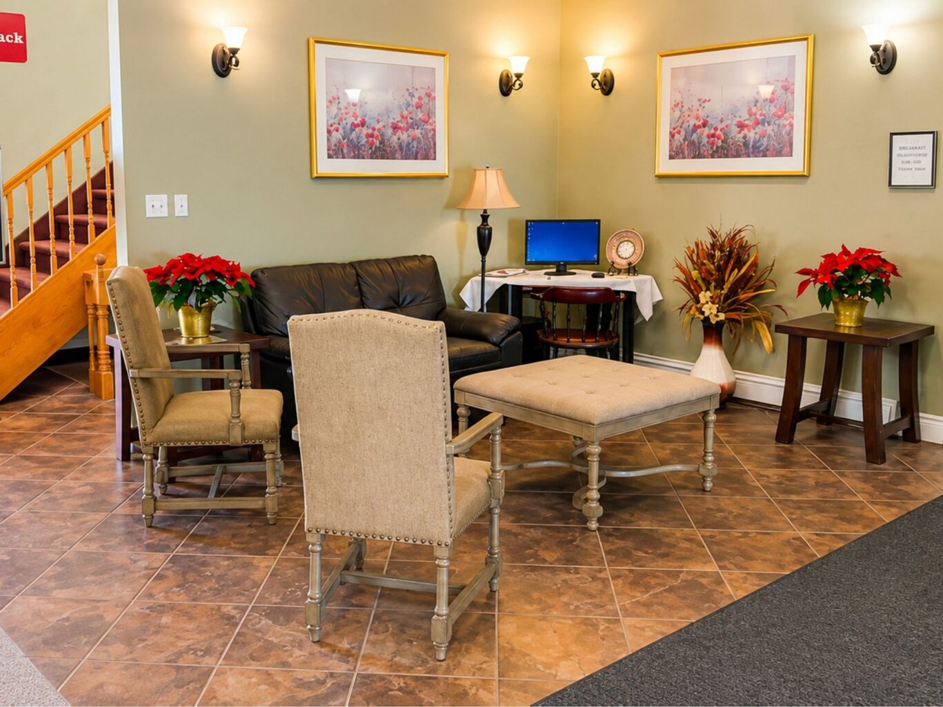Guest lounge at Travellers Inn Prince Edward Island with chairs, leather sofa, business desk, and warm lighting.