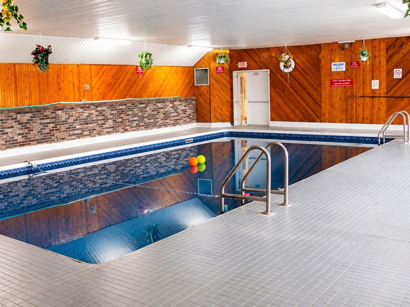 Indoor swimming pool with natural light and seating area at Travellers Inn Prince Edward Island.