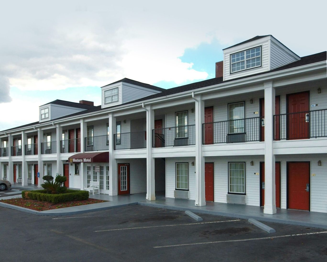 Exterior view of Western Motel Fitzgerald with red doors, white siding, and guest parking area