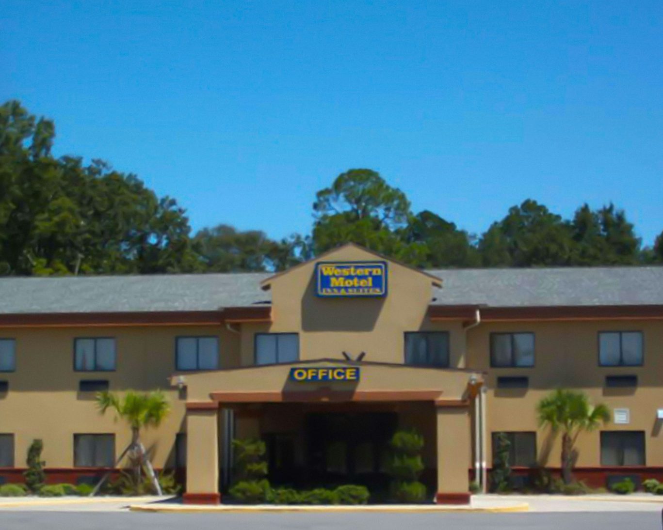 Exterior view of Western Motel in Hazlehurst, Georgia with front office and palm trees.