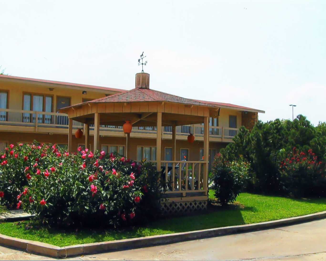 Exterior of Will Rogers Inn with gazebo and blooming rose garden in the courtyard.
