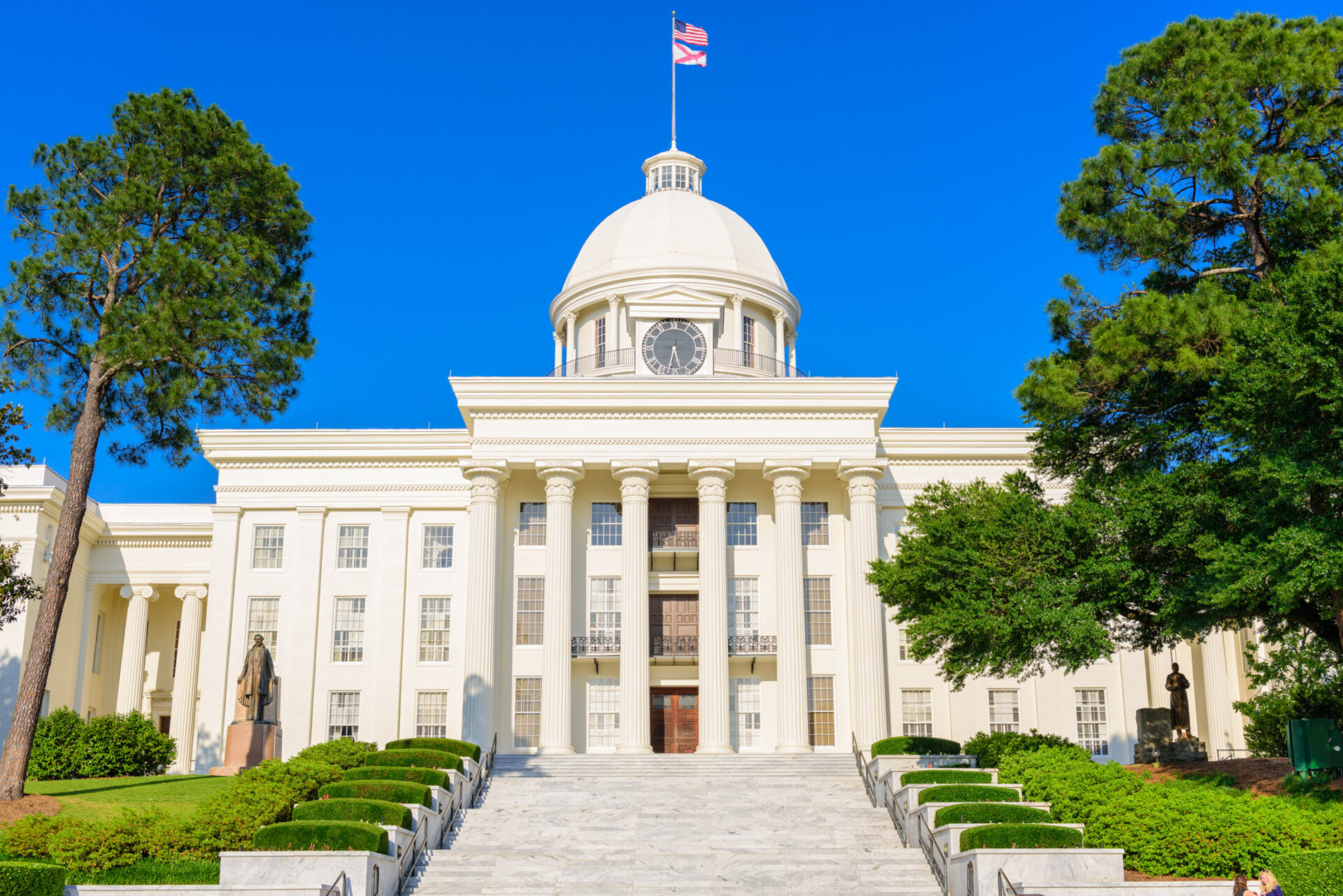 Alabama State Capitol building in Montgomery with white columns and dome under clear blue sky