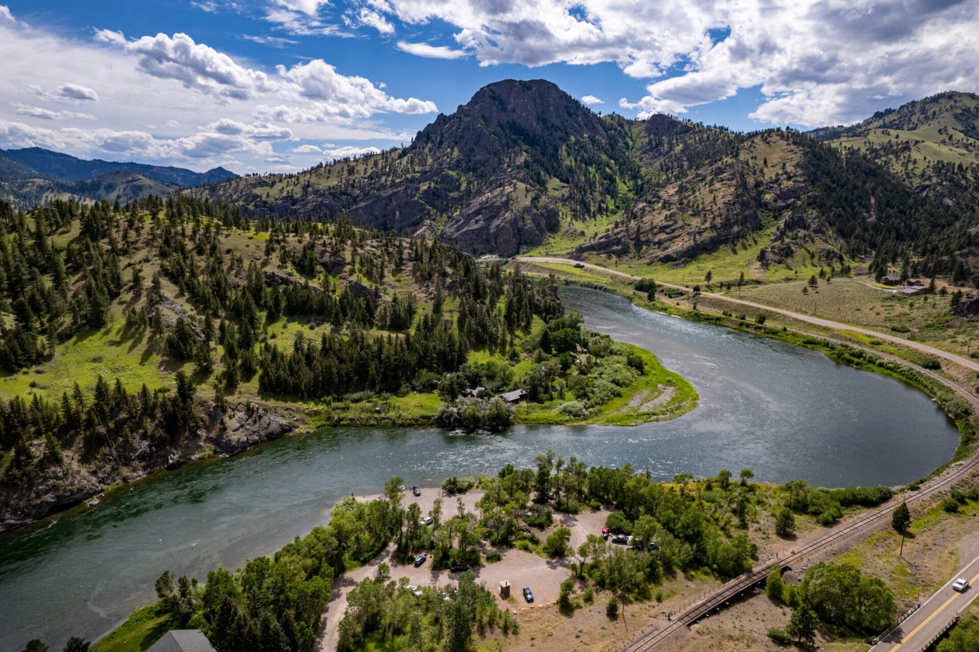 Aerial view of the Upper Missouri River winding through mountainous terrain in Montana under a partly cloudy sky.