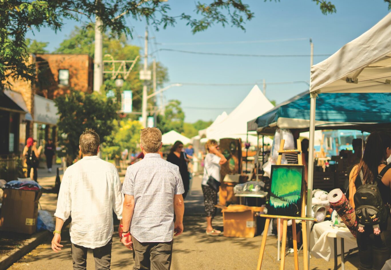 two men walking through a local street with art